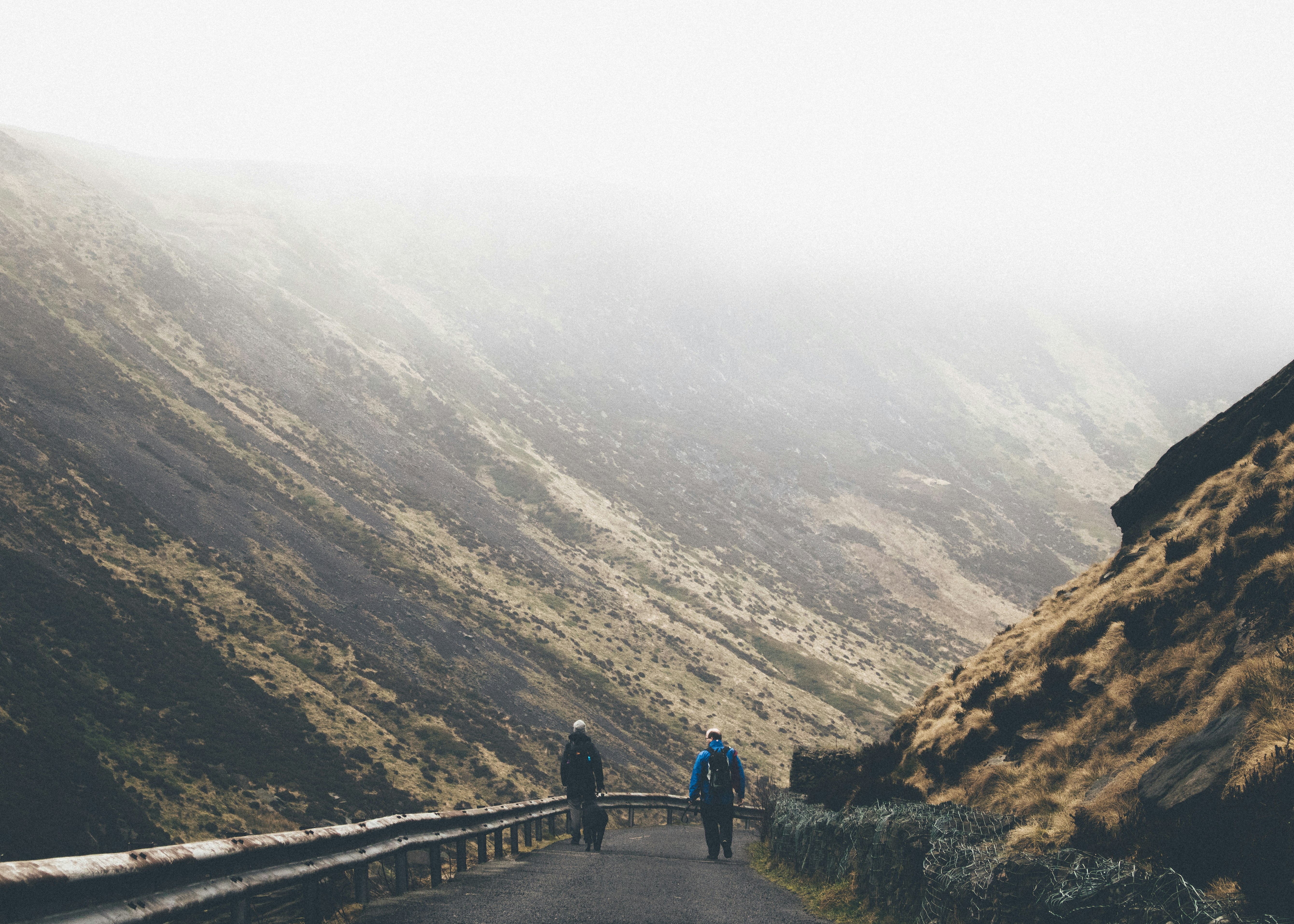 man wearing blue jacket walking on road